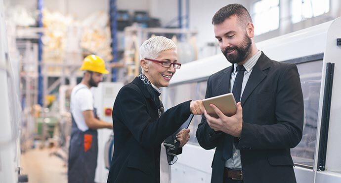 Man and woman on building site looking at iPad