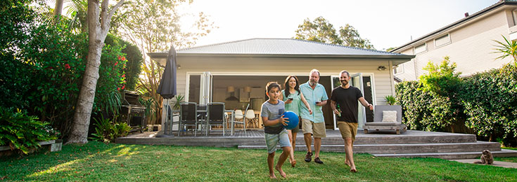 Family in back yard of Australian house on grass with blue ball