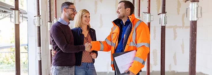 Couple shaking hands with depreciation inspector inside house undergoing renovation