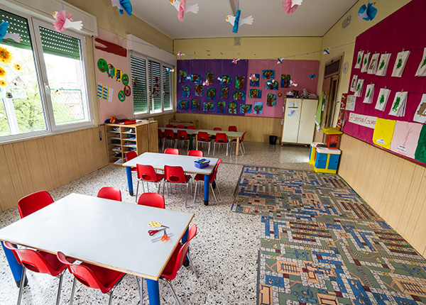 indoor childcare centre room with common assets such as small tables & chairs and bookcases