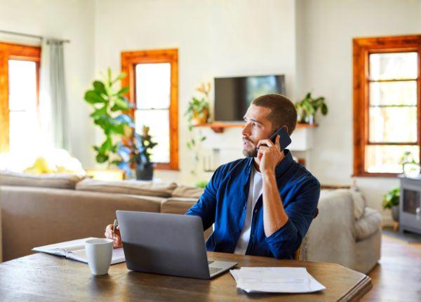 Man sitting at table in dining room on the phone enquiring about landlord insurance loss of rent