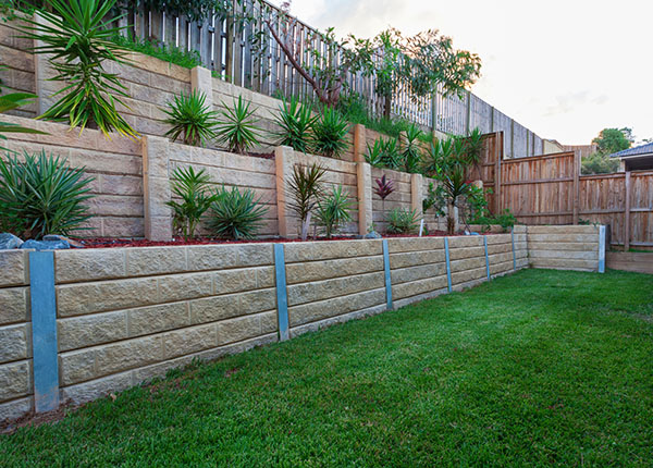 australian rental property backyard including 3 multi-level retaining walls with plants and red rock