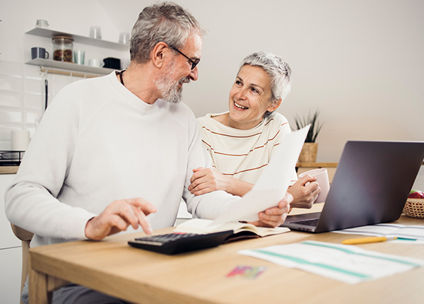 Older couple completing tax return sitting at kitchen table