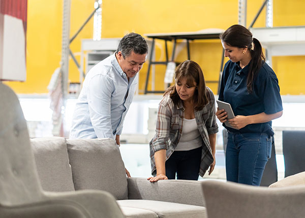 Interior stylist with clients looking at grey couch