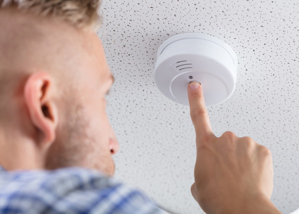 man checking a smoke alarm in a rental property